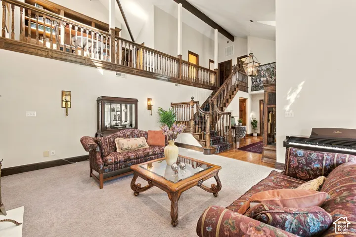 Carpeted living area with a dark wood open-tread staircase and a second-story balcony featuring built-in shelving