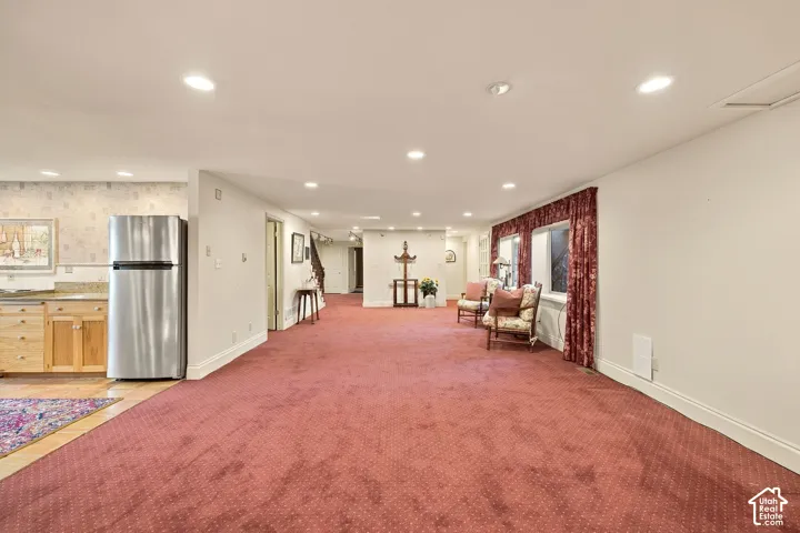 Recessed lighting throughout, stainless steel refrigerator, wood cabinetry, stone countertops, and multiple windows with drapery