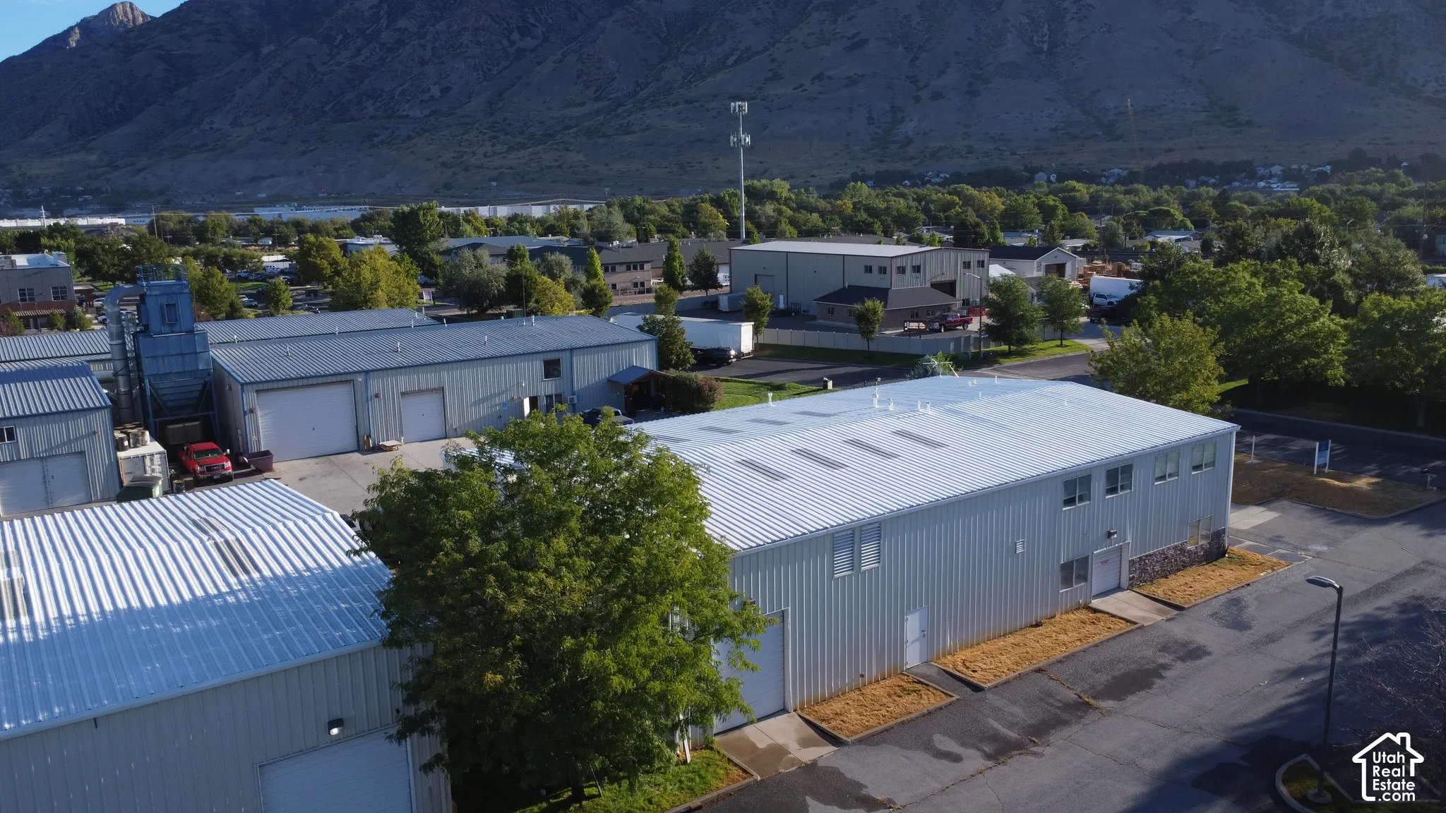Metal-sided commercial building with multiple windows, a stone foundation, and a large paved parking area