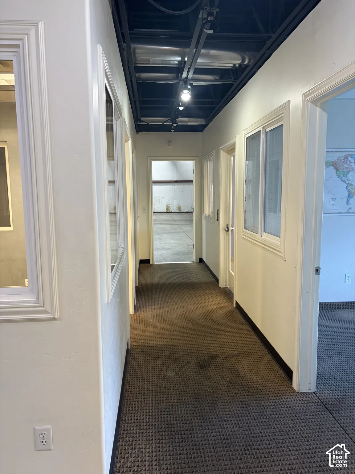 Hallway featuring textured carpeting, white walls, and track lighting