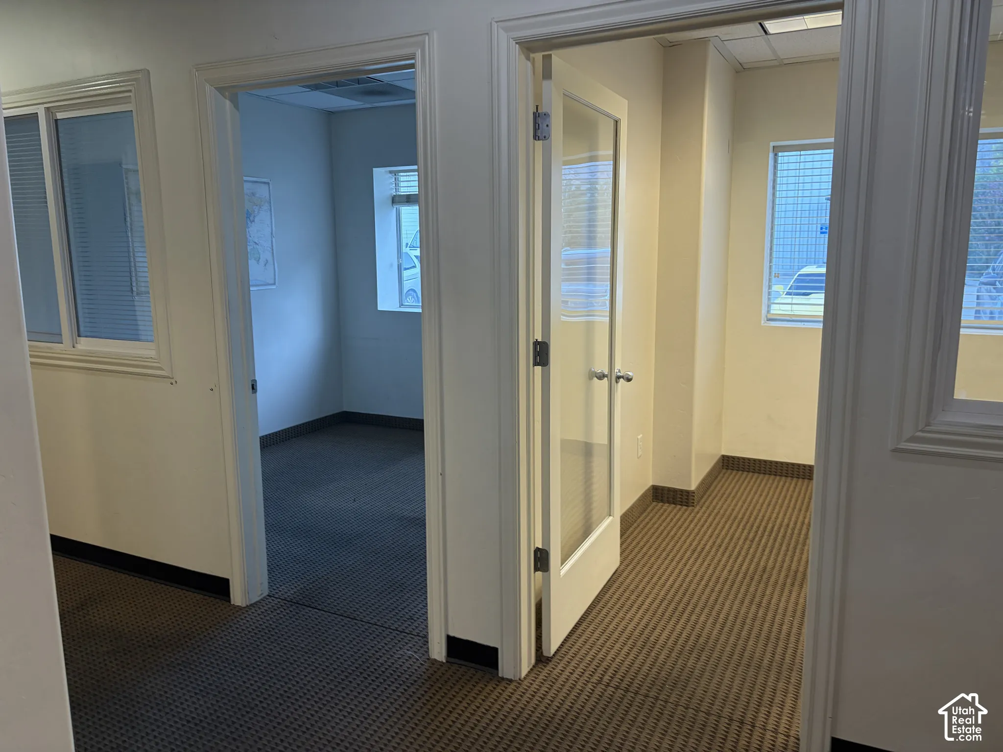 Two distinct rooms with textured carpet flooring, white walls, and white window blinds