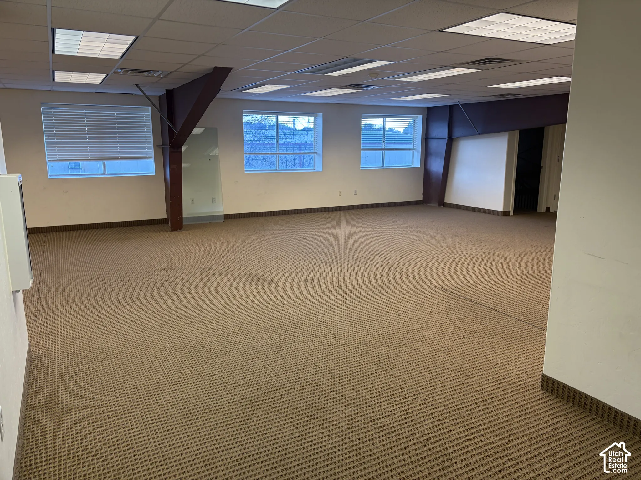Carpeted open-concept space with multiple windows and recessed ceiling lighting