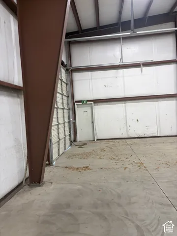 Concrete flooring with a white paneled wall and a roll-up door
