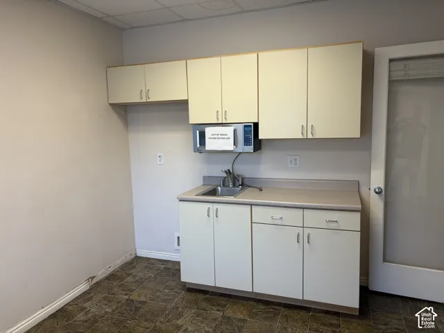 Built-in cabinetry with a laminate countertop, stainless steel sink, and wood-finish flooring