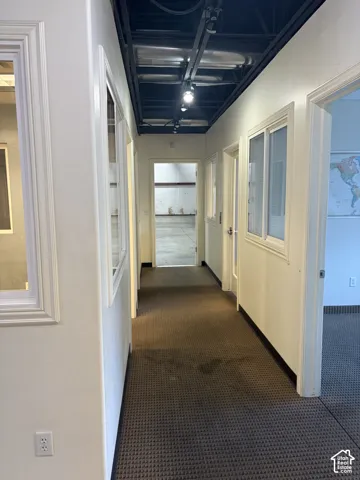 Hallway featuring textured carpeting, white walls, and track lighting