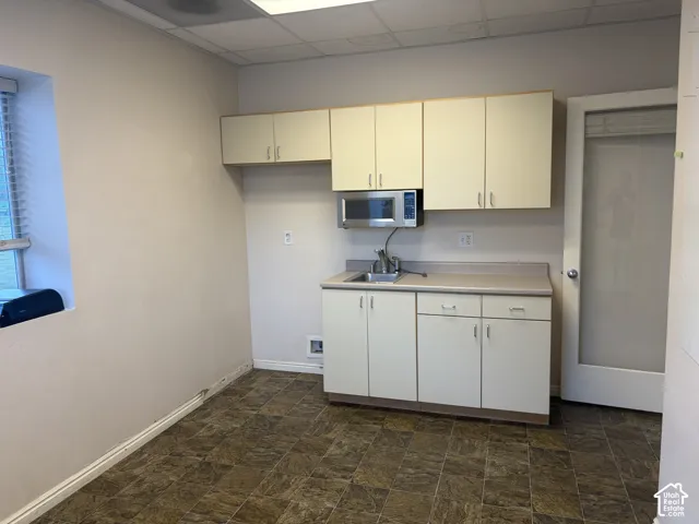 Compact kitchen area featuring a stainless steel microwave, single basin sink, and ample cabinetry