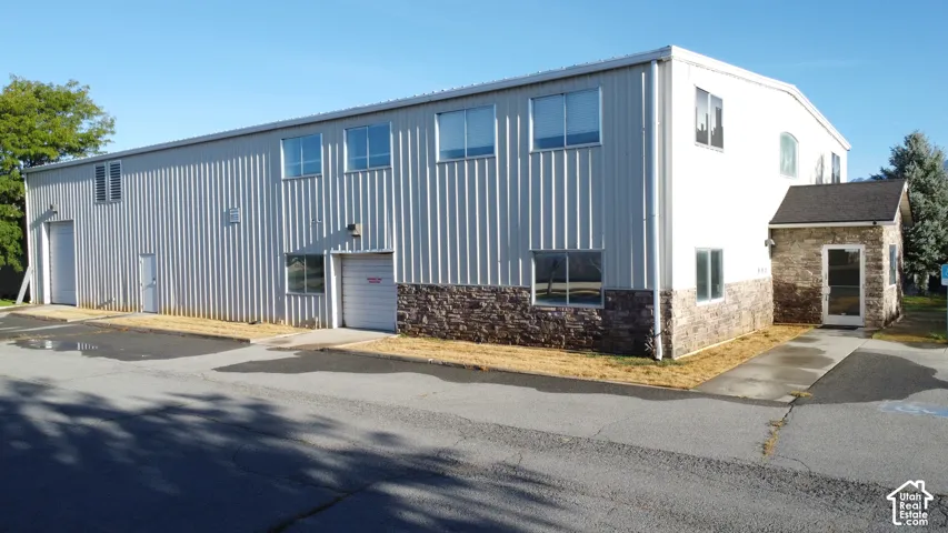 Metal-clad exterior, stone veneer accents, multiple windows, roll-up garage doors, covered entry