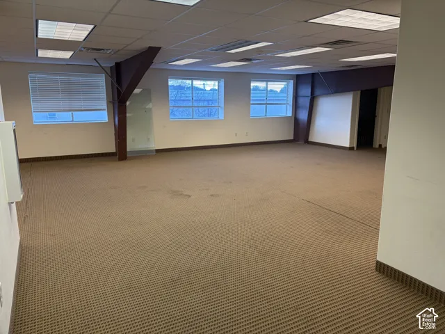 Carpeted open-concept space with multiple windows and recessed ceiling lighting