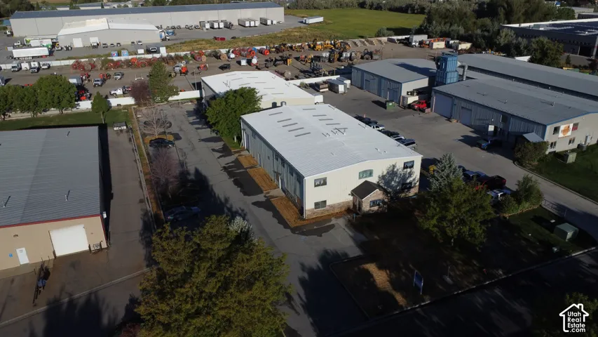 Commercial property featuring multiple industrial buildings with light-colored roofs, paved driveways, and surrounding green spaces
