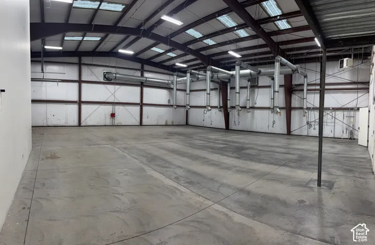 Expansive concrete flooring in a large open space, featuring multiple overhead lighting fixtures and extensive ceiling-mounted ductwork