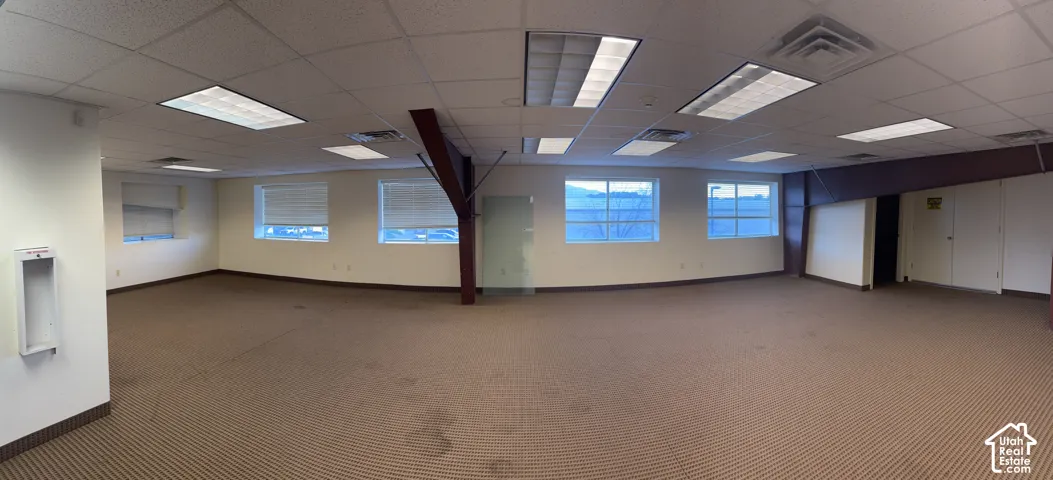 Expansive room with neutral-toned carpet, multiple windows, recessed lighting, and a suspended ceiling