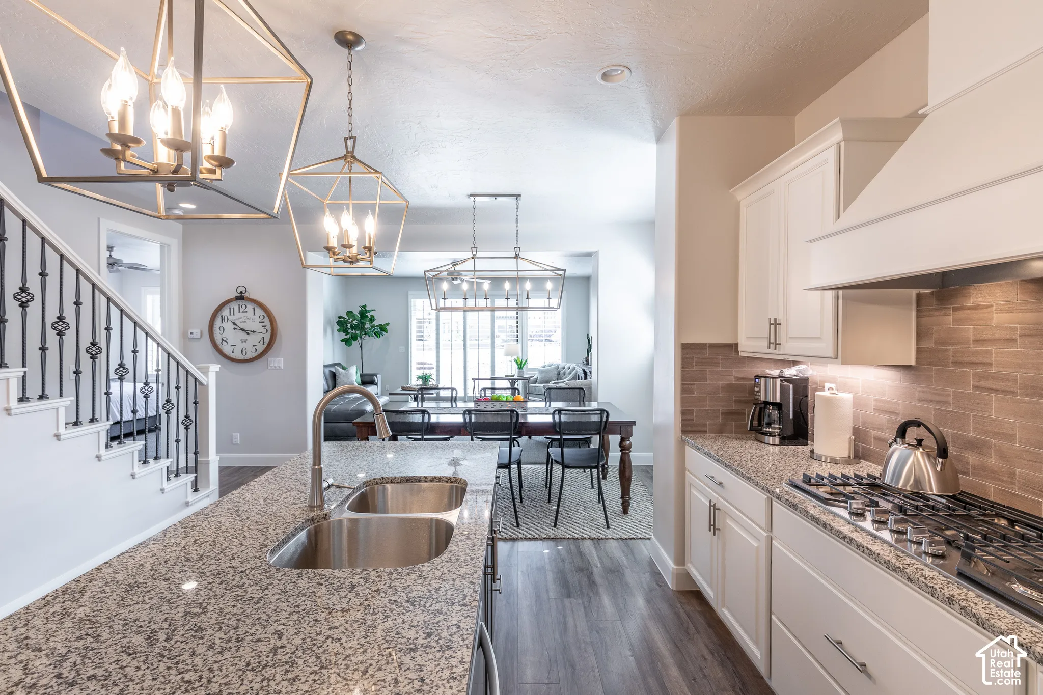 Granite countertops, dual stainless steel sink, wood-finish flooring, white cabinetry, and a gas range