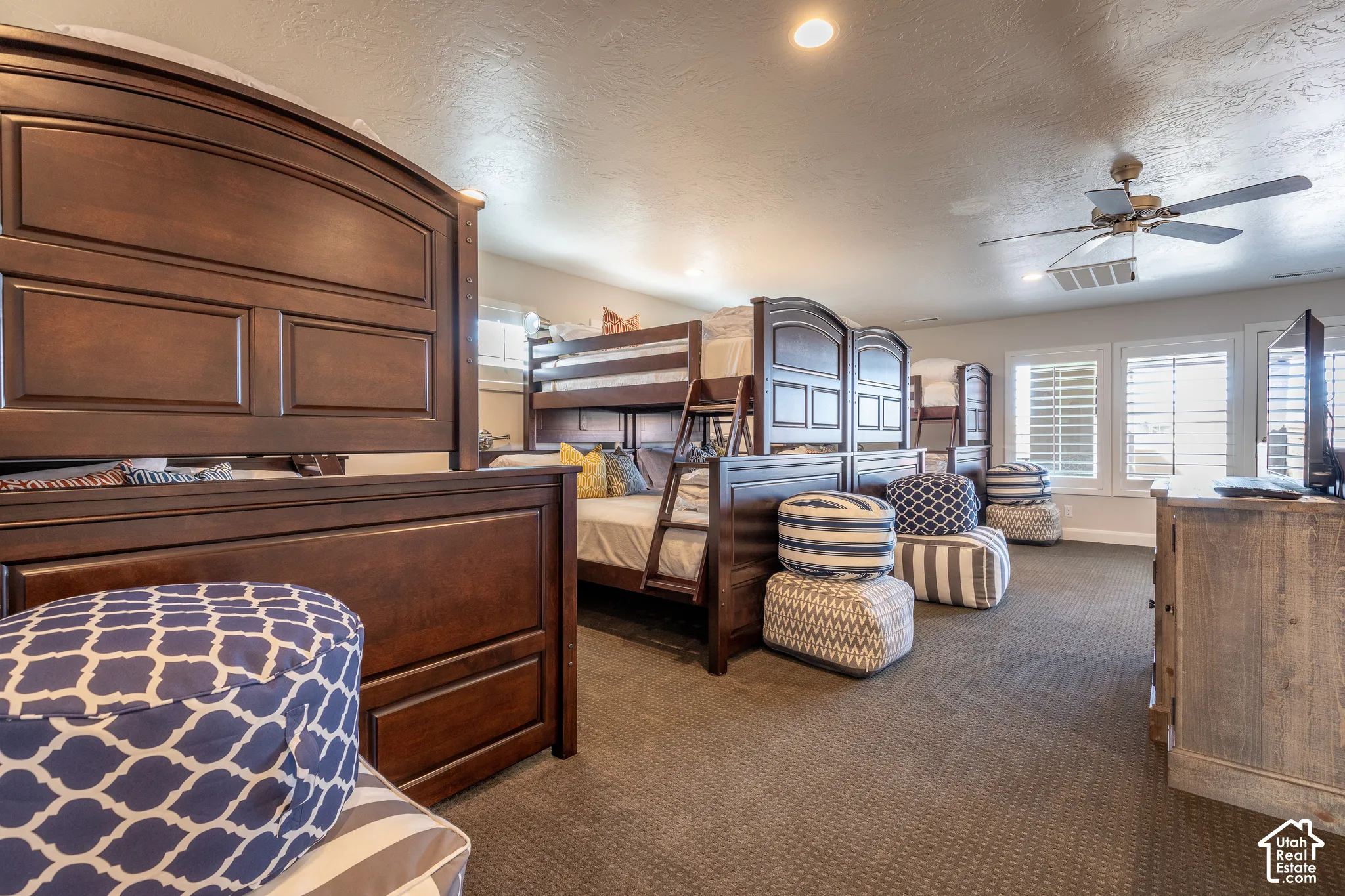 Spacious interior featuring recessed lighting, a ceiling fan, multiple windows with plantation shutters, and textured carpeting
