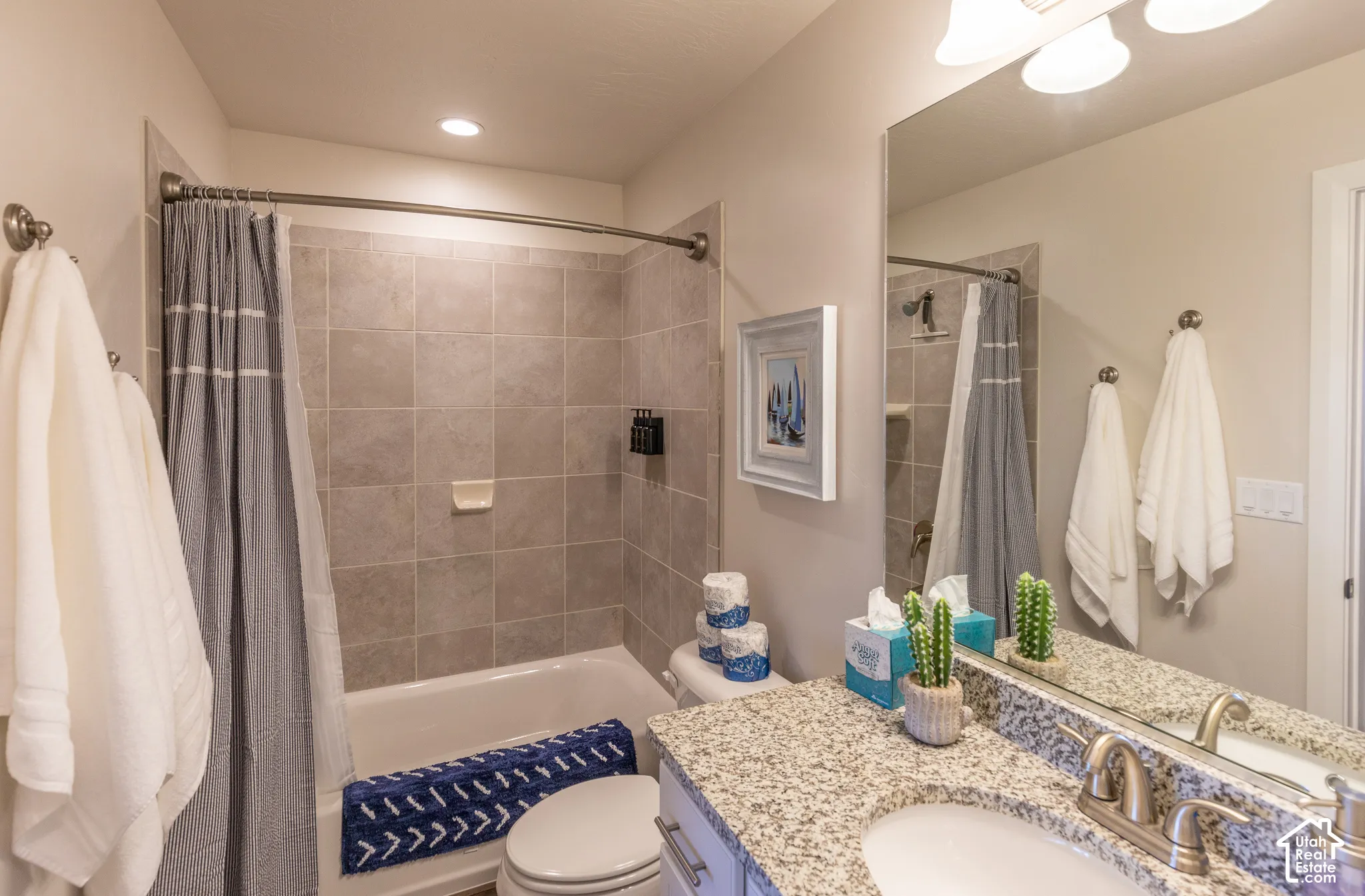 Bathroom featuring a bathtub with tiled surround, a vanity with a light-colored countertop, and a built-in mirror