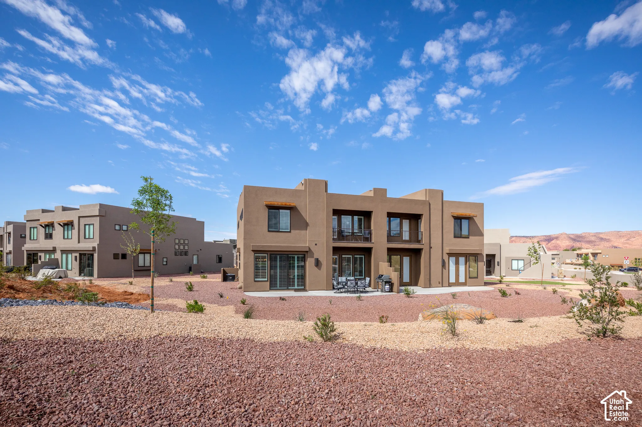 Southwestern-style exterior with a patio, upper-level balconies, and a rock-landscaped yard