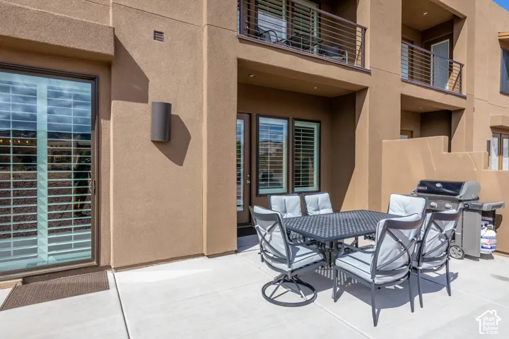 Paved patio with stucco exterior, sliding glass door, and exterior wall lighting