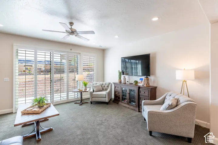 Recessed ceiling lighting, ceiling fan, sliding glass doors with plantation shutters, wall-mounted display, and carpeted flooring