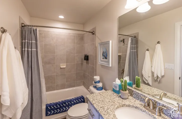 Bathroom featuring a bathtub with tiled surround, a vanity with a light-colored countertop, and a built-in mirror