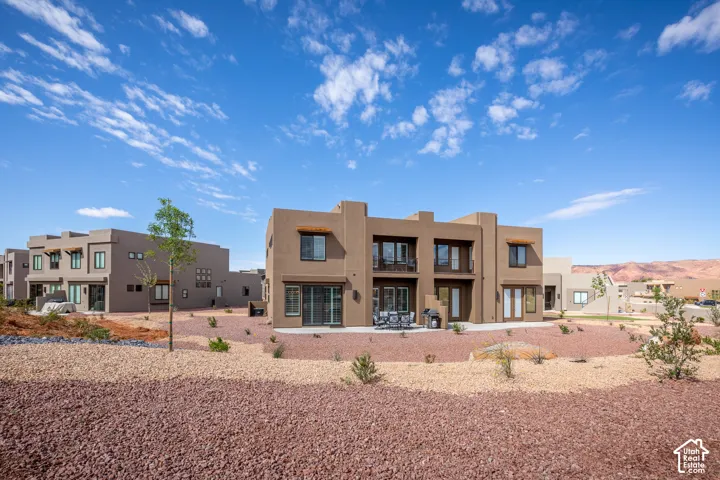 Southwestern-style exterior with a patio, upper-level balconies, and a rock-landscaped yard
