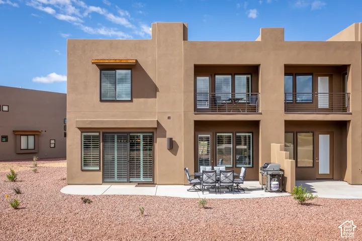 Stucco exterior with multiple balconies, ground-level patio, and sliding glass doors