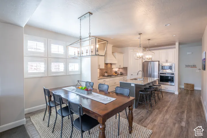 Wood-finish flooring, white cabinetry, stainless steel appliances, and a kitchen island with seating