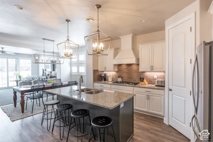 Open-concept kitchen featuring an oversized island with granite countertop, stainless steel appliances, a tile backsplash, and wood-finish flooring