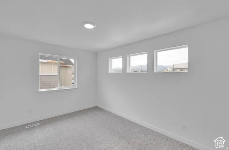 Recessed ceiling lighting, light gray wall-to-wall carpeting, white walls, and multiple windows