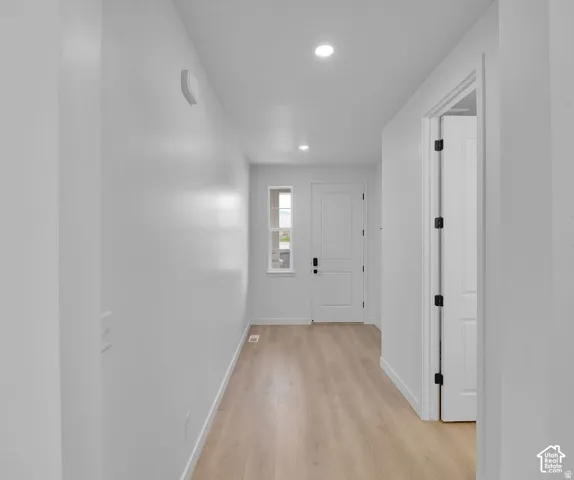 Entryway featuring wood-finish flooring, recessed lighting, and a white paneled door with matte black hardware