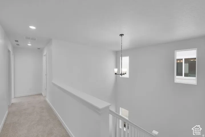 Stairwell and upper hall featuring recessed lighting, a modern chandelier, and two windows