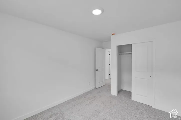 Recessed lighting illuminates a space featuring new carpeting, a built-in closet with sliding doors, and a paneled door with dark hardware