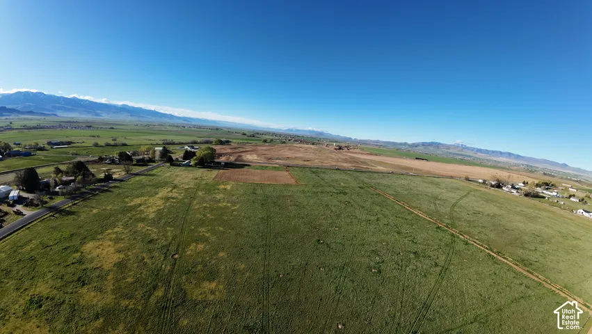 Expansive agricultural land featuring a verdant field and distant mountainous terrain