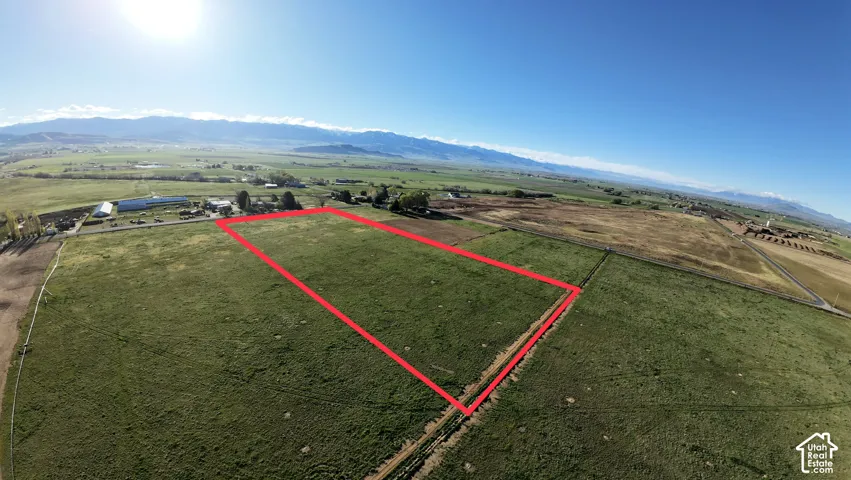 Expansive land parcel featuring clear boundaries, a vibrant green field, and distant mountain backdrops