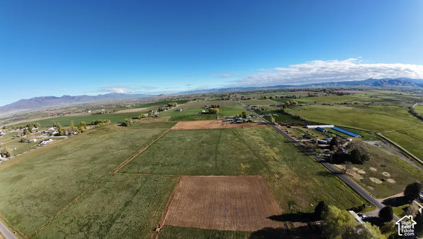 Expansive land parcel with clear boundaries, bordering a paved road, and featuring distant mountain ranges