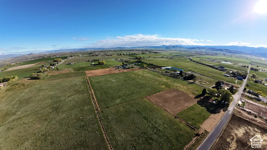 Expansive rural landscape featuring open fields, distant mountains, and a clear sky