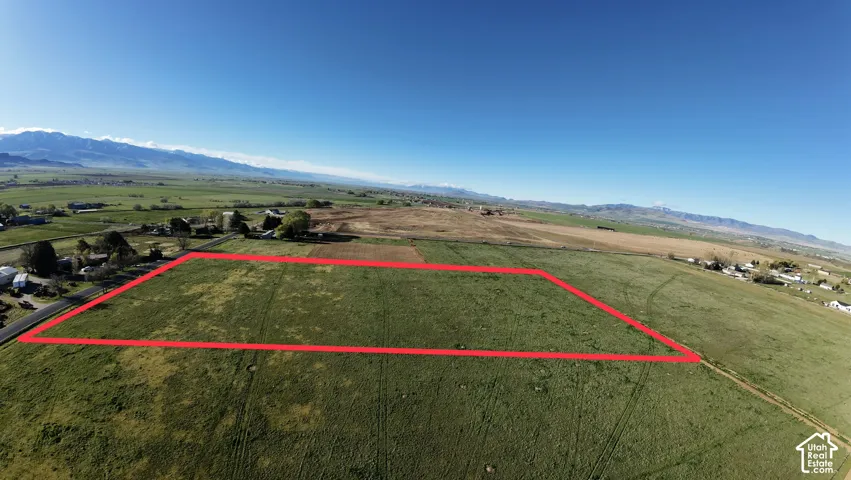 Expansive rural property featuring a green field and distant mountain ranges