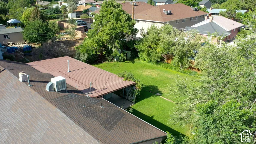 Expansive backyard featuring a manicured lawn, established trees, and a covered patio area