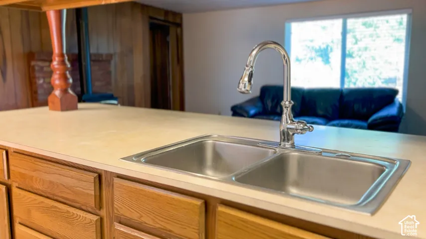 Kitchen island with a double basin stainless steel sink, chrome faucet, and wood-finish cabinetry