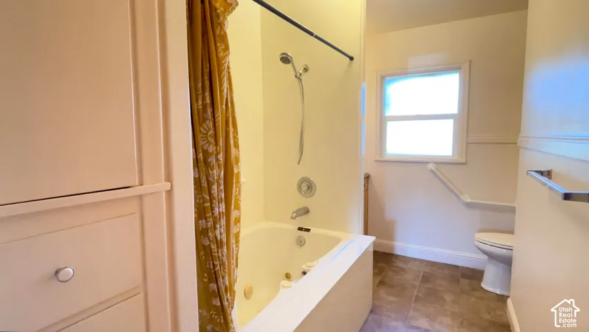 Built-in storage cabinetry, tiled flooring, built-in bathtub, and window with privacy glass