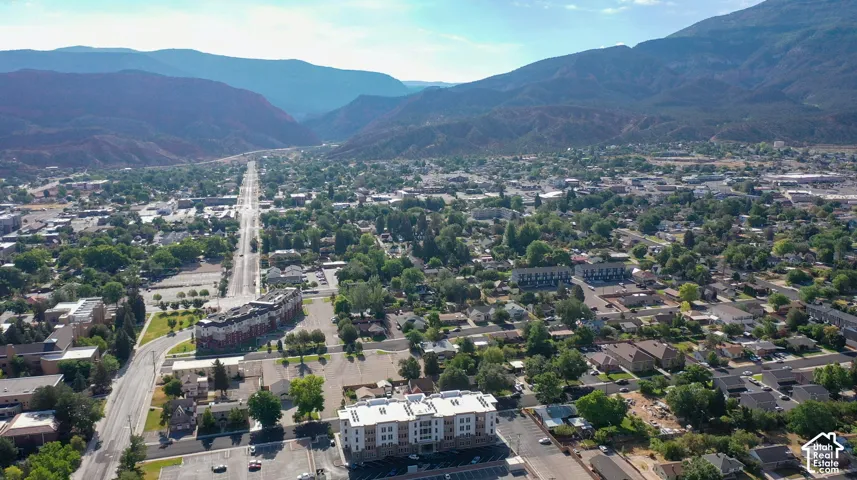 Expansive mountain backdrop, urban environment, mature trees, multi-story buildings, and visible roadways