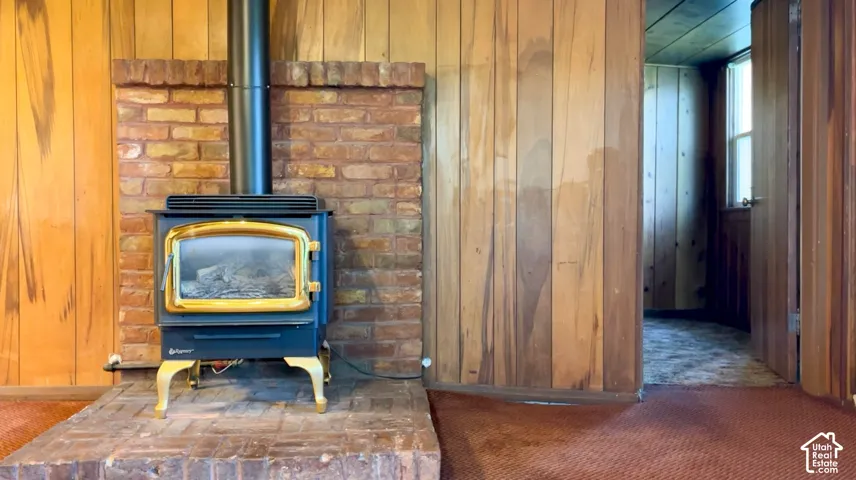 Wood-paneled walls featuring a brick fireplace with a wood-burning stove