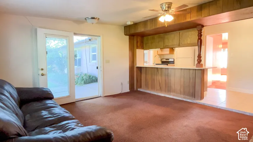 Wet bar featuring wood paneling, wood-finish cabinetry, and a ceiling fan