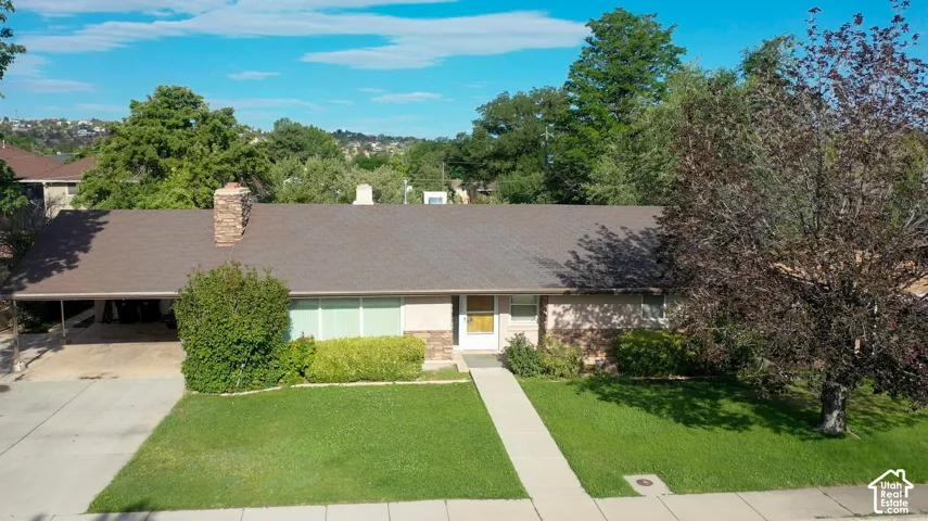 Single-story residence featuring a carport, stone facade accents, and a prominent stone chimney