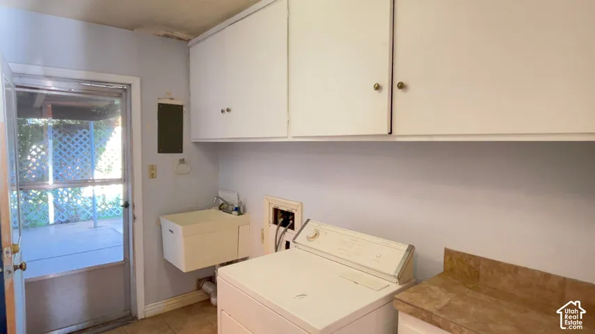 Laundry area featuring overhead cabinetry, a utility sink, and tiled flooring