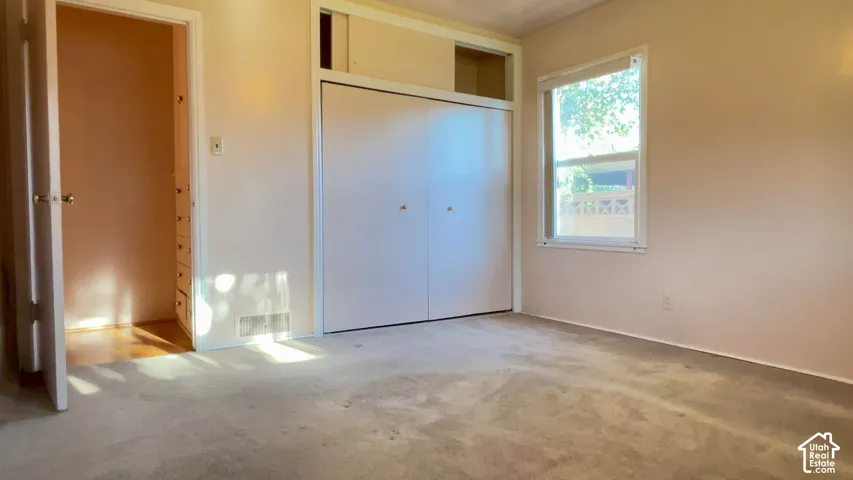 Carpeted flooring, white bi-fold closet doors, built-in dresser, and a window with exterior scenery