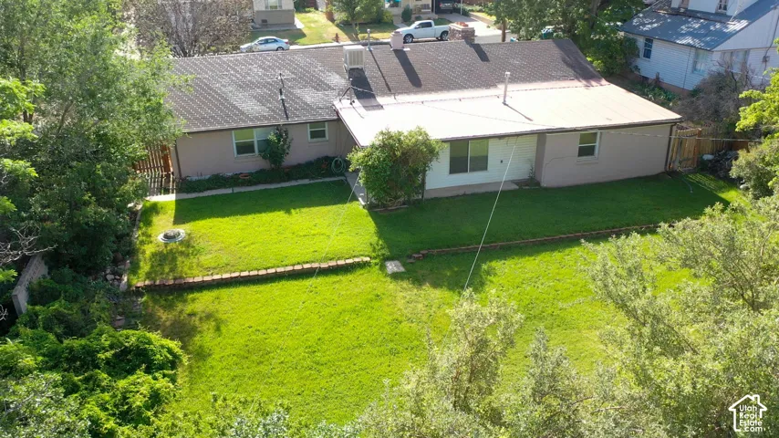 Expansive backyard featuring a manicured lawn, established trees, and a wooden privacy fence