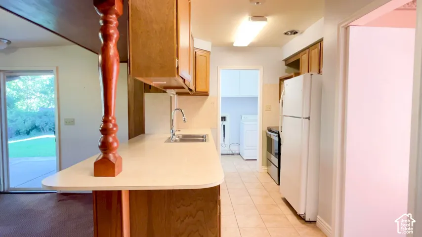 Kitchen featuring wood cabinetry, white appliances, and tiled flooring