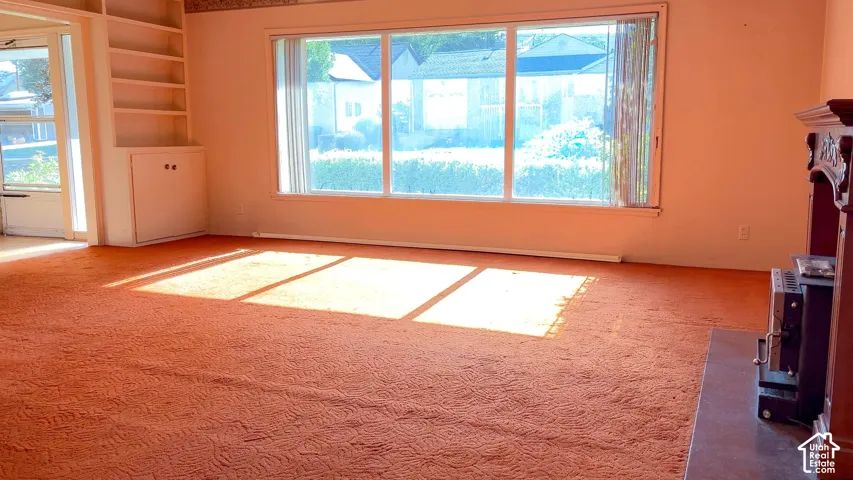 Built-in shelving, integrated lower cabinetry, large picture windows, and a decorative fireplace