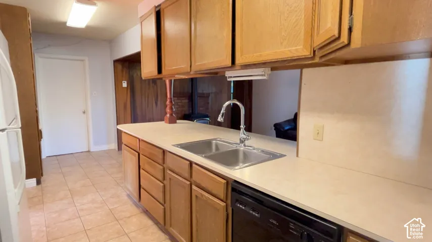 Kitchen featuring wood cabinetry, a double basin stainless steel sink with a high-arc faucet, and tiled flooring