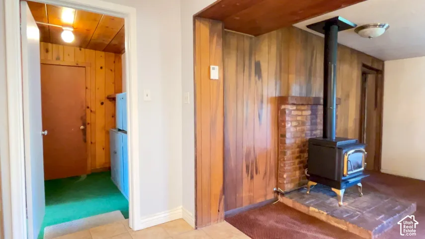 Wood-paneled wall with brick fireplace surround and a black wood-burning stove on a raised hearth