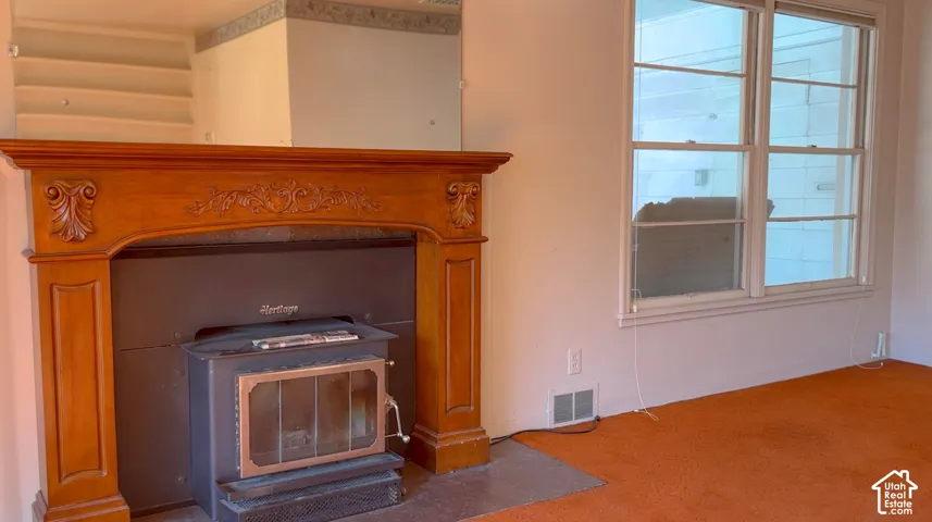 Wood-finish fireplace mantel with carved detailing, integrated wood-burning stove, and multi-pane windows